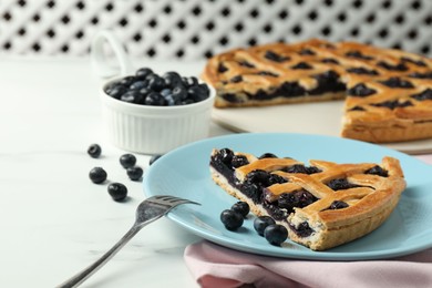 Photo of Piece of tasty homemade pie with blueberries served on white marble table