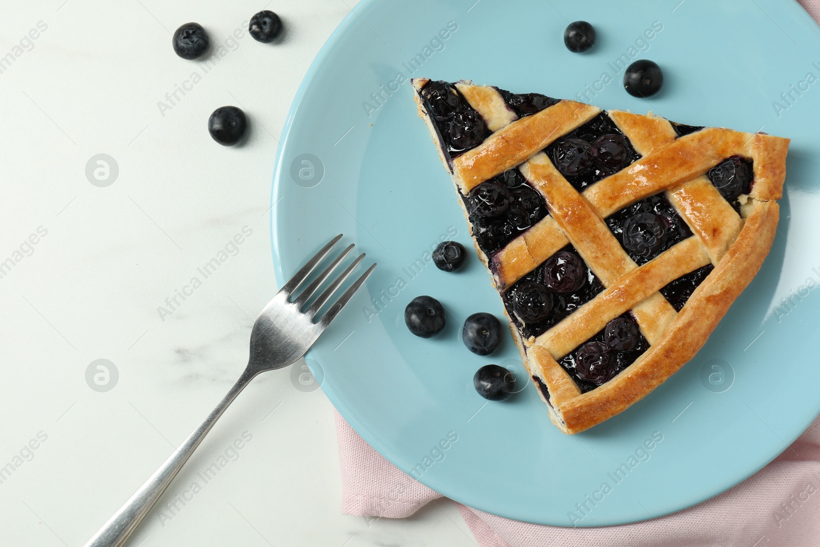 Photo of Piece of tasty homemade pie with blueberries served on white marble table, flat lay