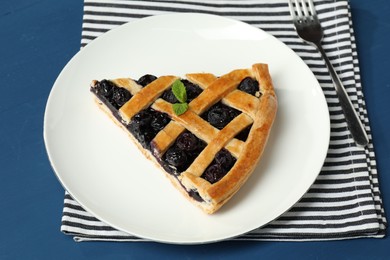 Photo of Piece of tasty homemade pie with blueberries served on blue table