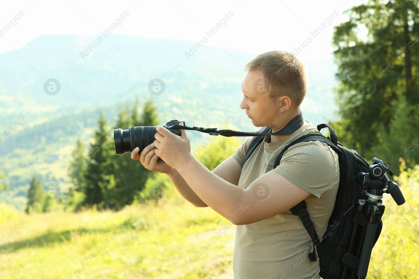 Photo of Photographer with backpack and camera taking picture of beautiful mountains