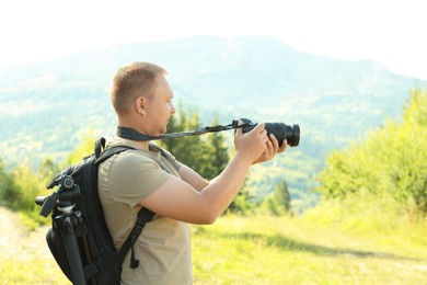 Photographer with backpack and camera taking picture of beautiful mountains