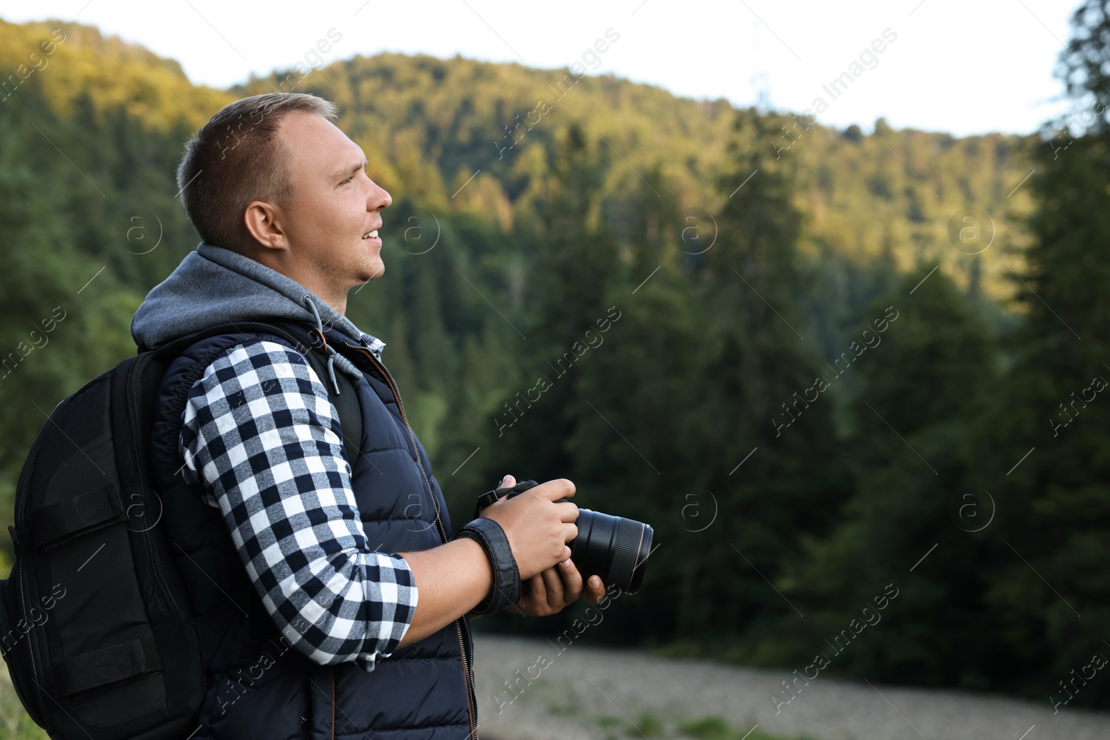 Photo of Photographer with backpack and camera in beautiful mountains. Space for text