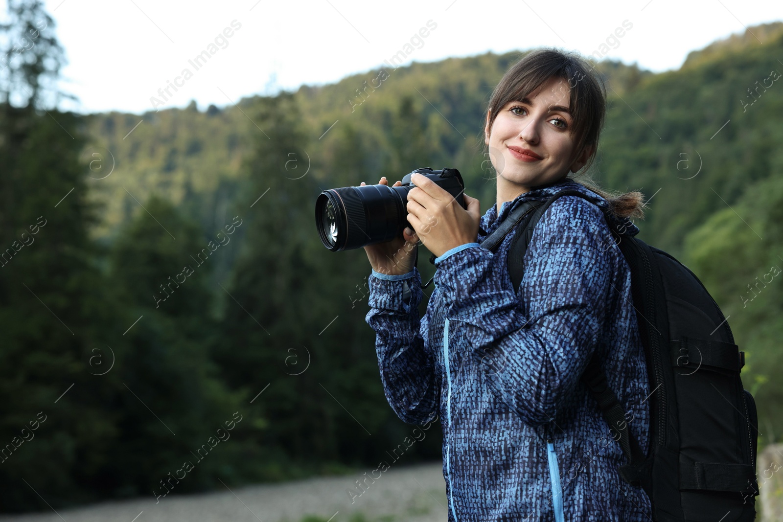 Photo of Photographer with backpack and camera outdoors, space for text