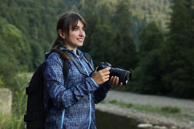 Photo of Smiling photographer with backpack and camera outdoors