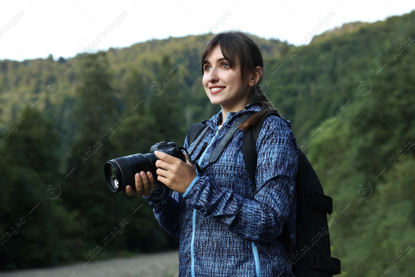 Photo of Smiling photographer with backpack and camera outdoors