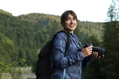 Photo of Smiling photographer with backpack and camera outdoors