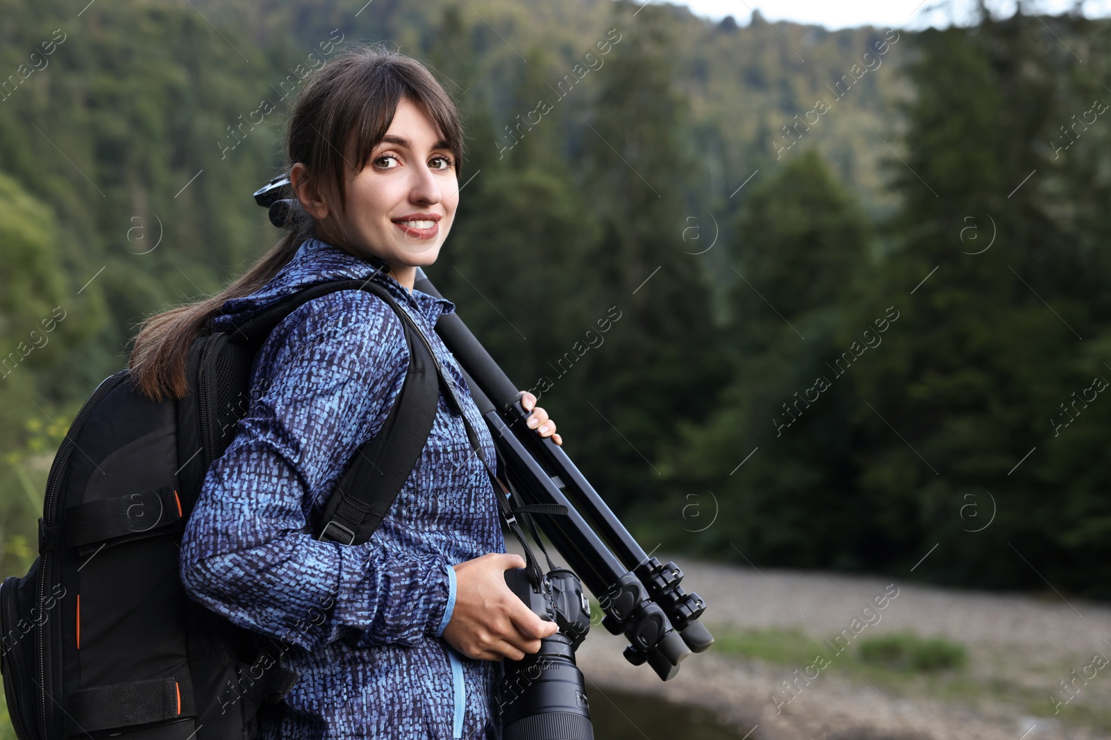 Photo of Photographer with backpack, camera and other professional equipment outdoors. Space for text