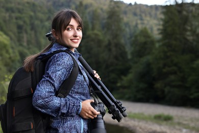 Photo of Photographer with backpack, camera and other professional equipment outdoors. Space for text