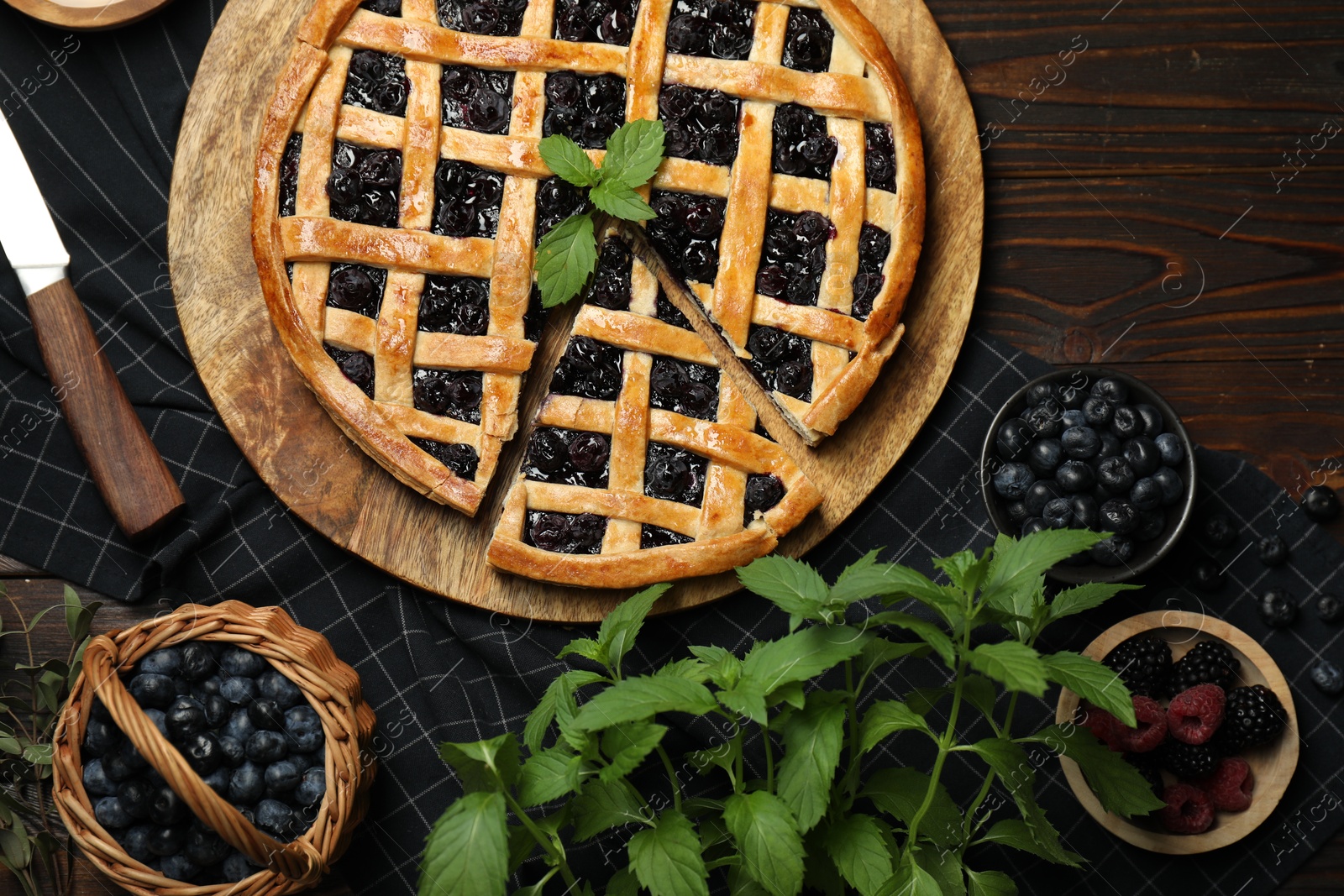 Photo of Tasty homemade pie with blueberries, fresh berries, mint, honey and knife on wooden table, flat lay