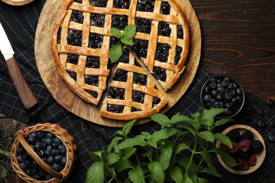 Photo of Tasty homemade pie with blueberries, fresh berries, mint, honey and knife on wooden table, flat lay