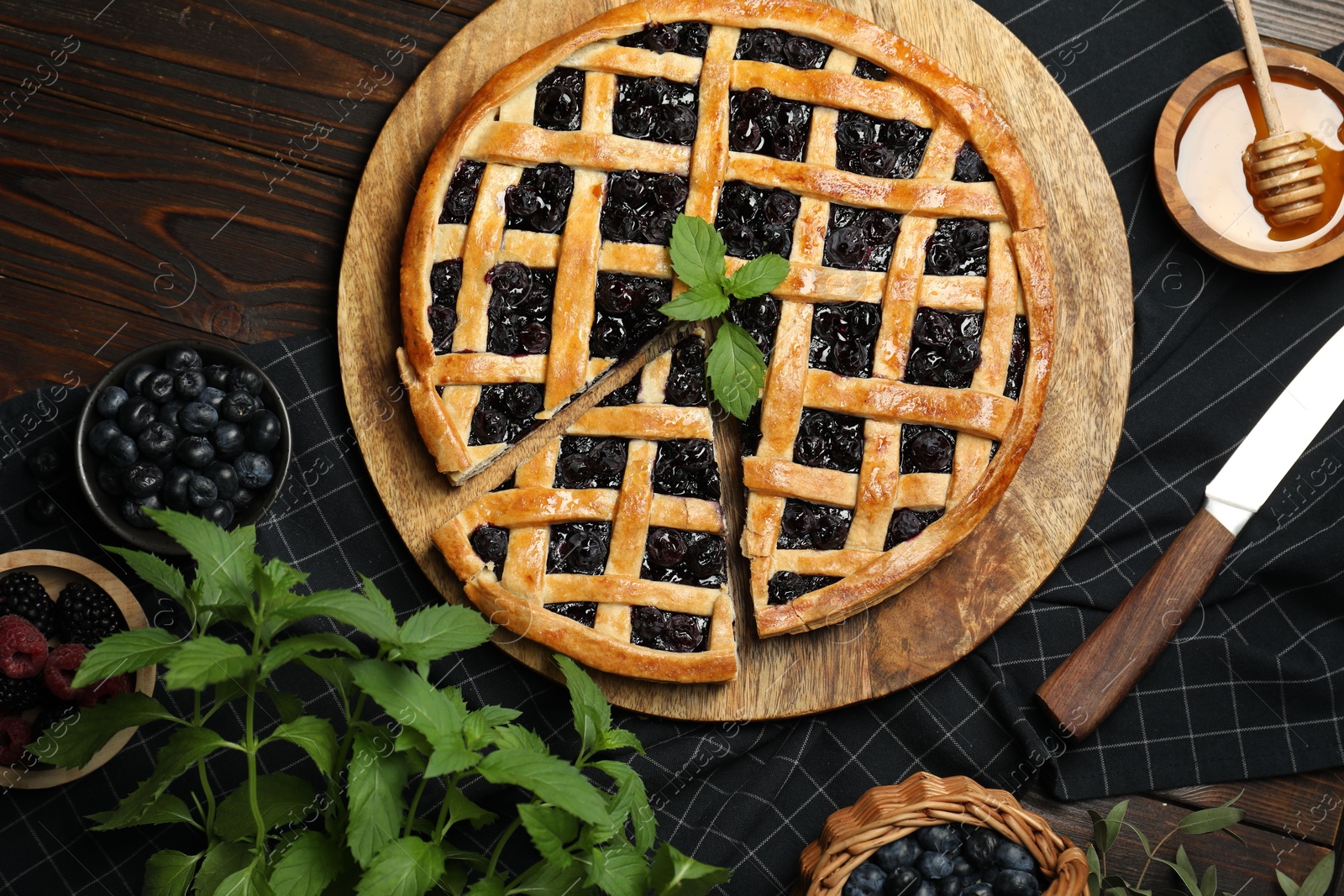 Photo of Tasty homemade pie with blueberries, fresh berries, mint, honey and knife on wooden table, flat lay