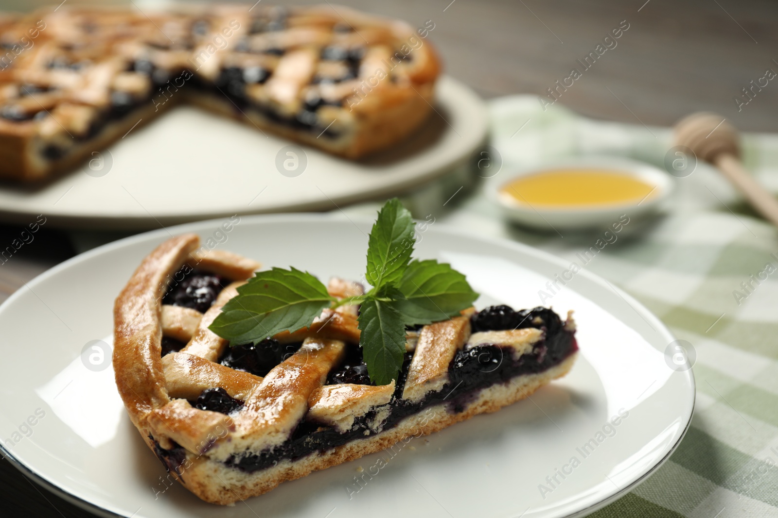 Photo of Piece of tasty homemade pie with blueberries and mint on table, closeup