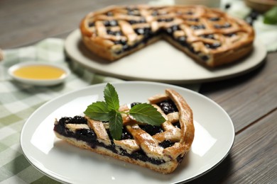 Photo of Piece of tasty homemade pie with blueberries and mint on table, closeup