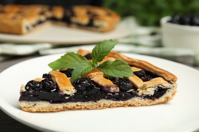 Photo of Piece of tasty homemade pie with blueberries and mint on table, closeup