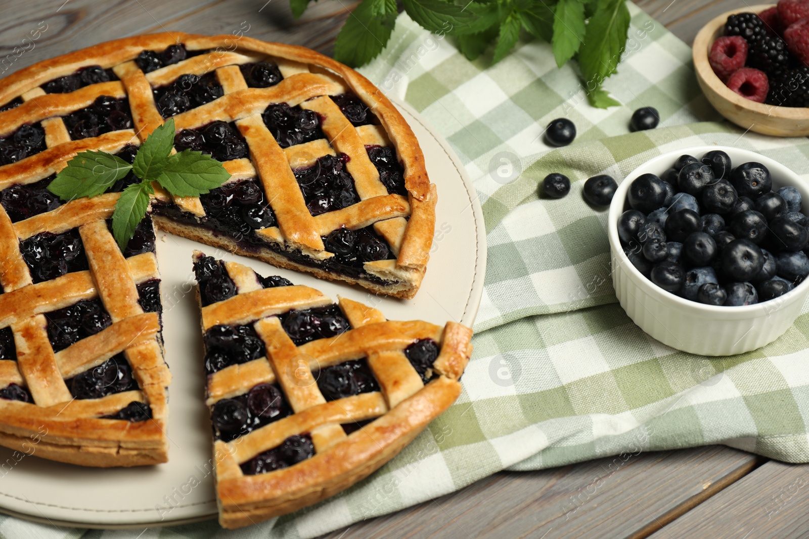 Photo of Tasty homemade pie with blueberries, fresh berries and mint on wooden table, closeup