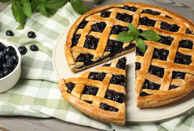 Tasty homemade pie with blueberries and mint on wooden table, closeup