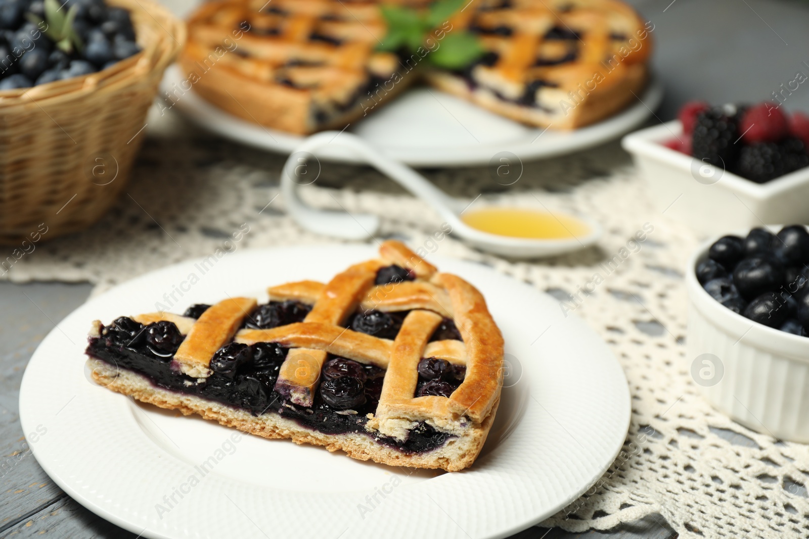 Photo of Piece of tasty homemade pie with blueberries on gray table, closeup