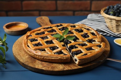 Photo of Taking piece of tasty homemade pie with blueberries at blue wooden table, closeup