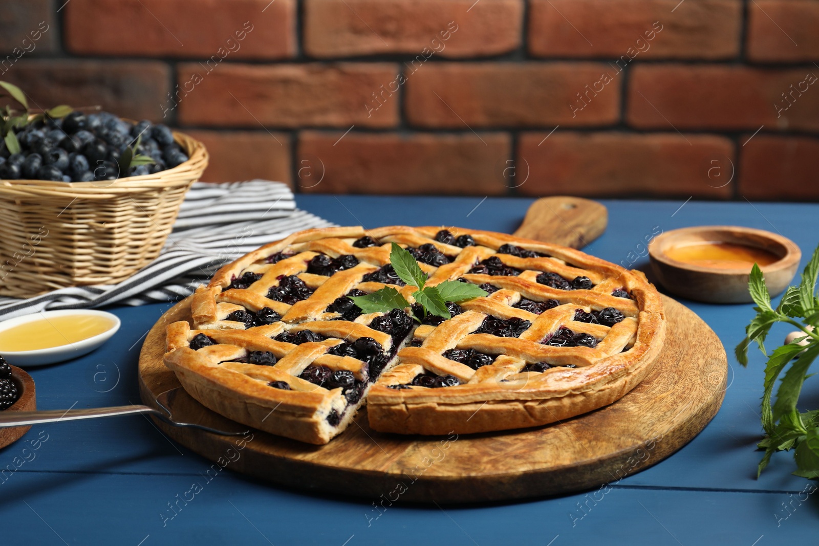 Photo of Taking piece of tasty homemade pie with blueberries at blue wooden table, closeup