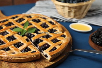 Photo of Taking piece of tasty homemade pie with blueberries at blue wooden table, closeup