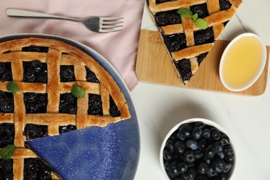 Photo of Tasty homemade pie with blueberries, honey and fork on white table, flat lay