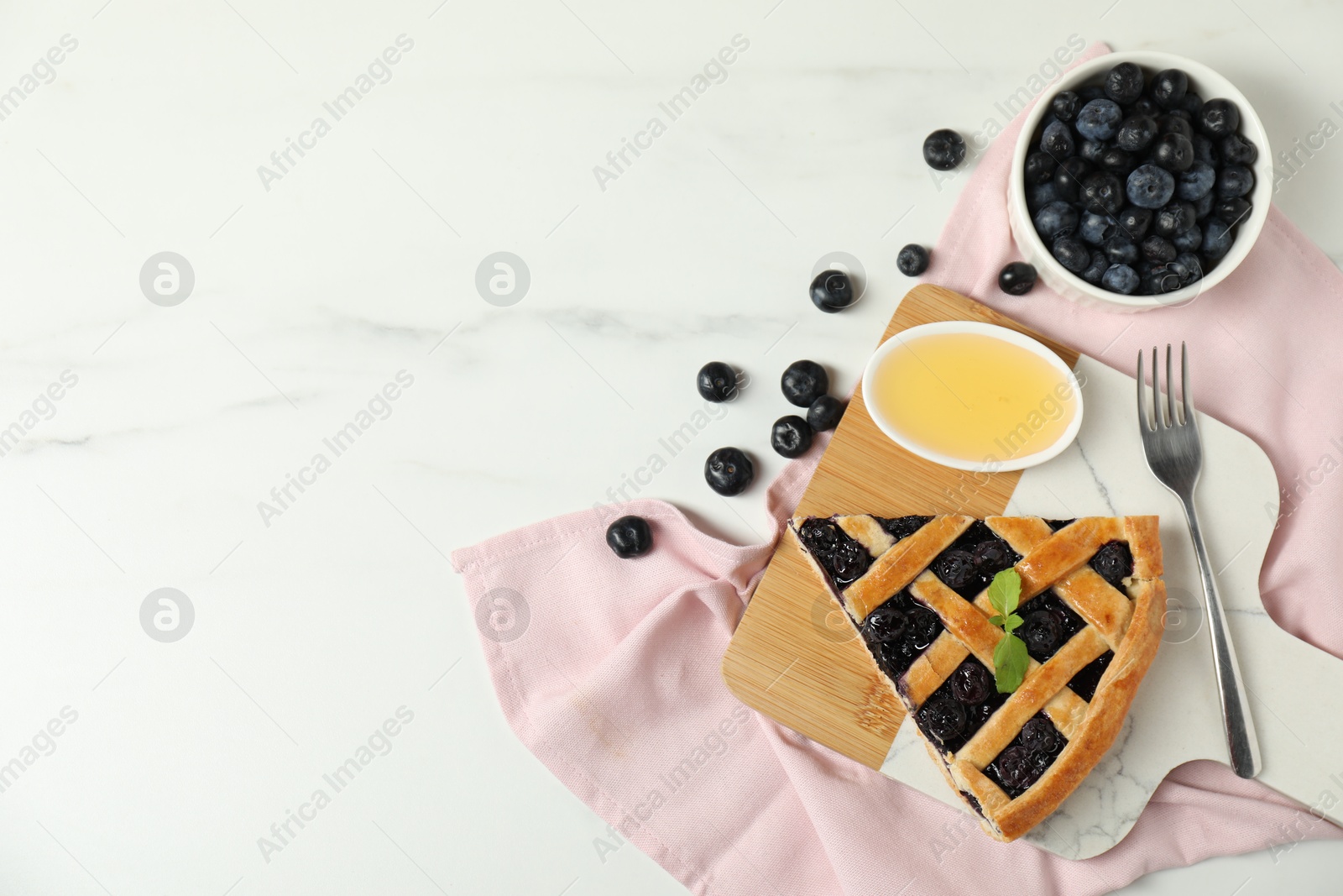 Photo of Piece of tasty homemade pie with blueberries, honey and fork on white marble table, flat lay. Space for text