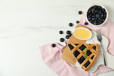 Piece of tasty homemade pie with blueberries, honey and fork on white marble table, flat lay. Space for text