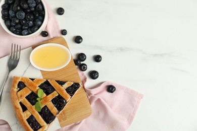 Photo of Piece of tasty homemade pie with blueberries, honey and fork on white marble table, flat lay. Space for text