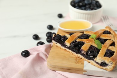 Photo of Piece of tasty homemade pie with blueberries on white table, closeup