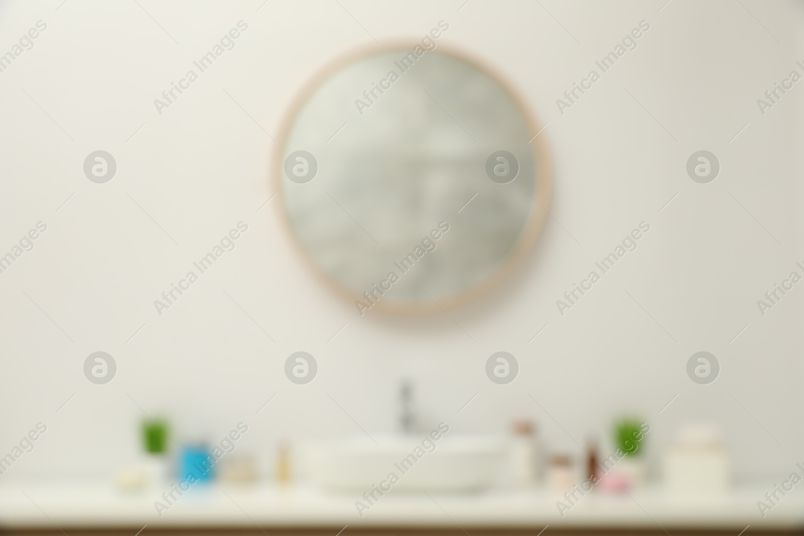 Photo of Blurred view of countertop with sink, houseplants and mirror in bathroom