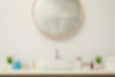 Photo of Blurred view of countertop with sink, houseplants and mirror in bathroom