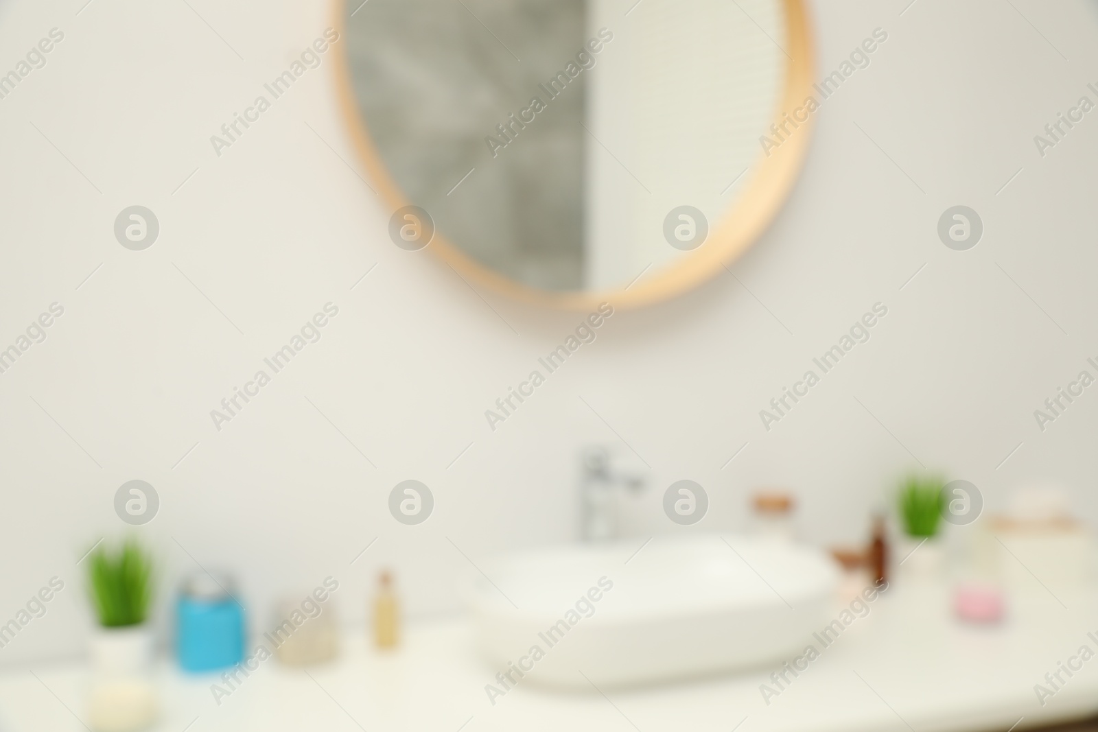 Photo of Blurred view of countertop with sink, houseplants and mirror in bathroom