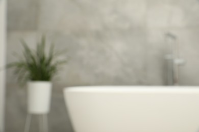 Photo of Blurred view of bath tub and houseplant in bathroom