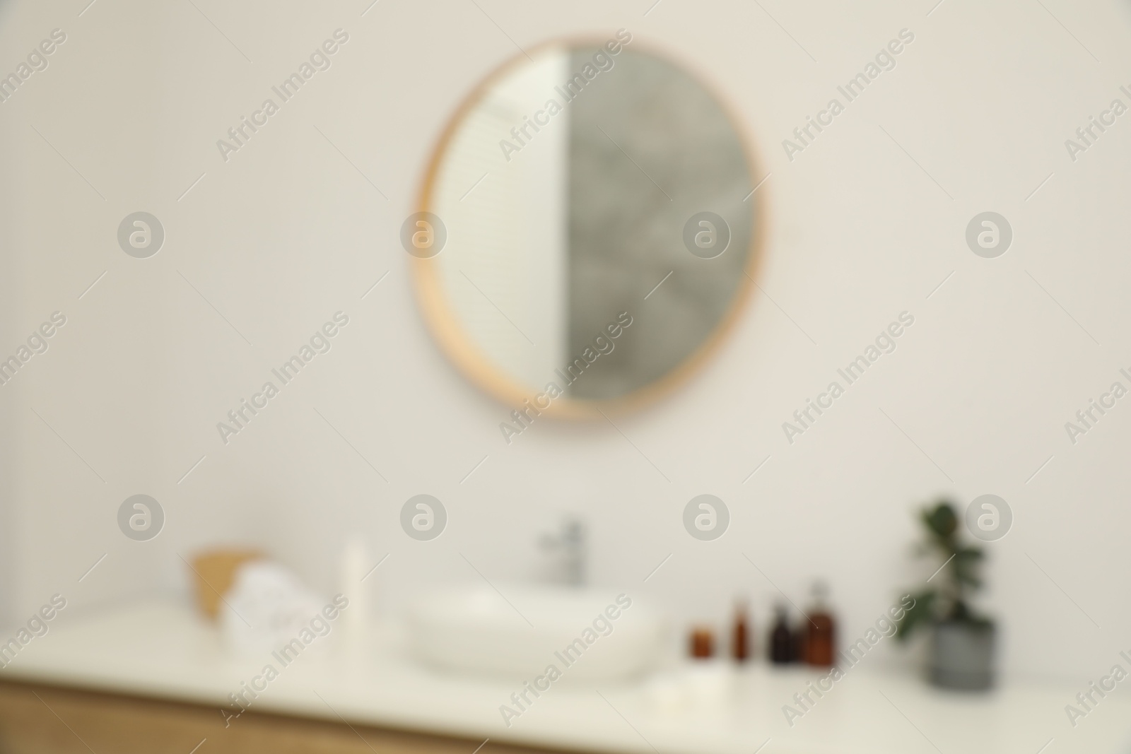 Photo of Blurred view of countertop with sink, towels, houseplant and mirror in bathroom