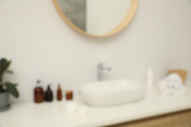 Photo of Blurred view of countertop with sink, towels, houseplant and mirror in bathroom