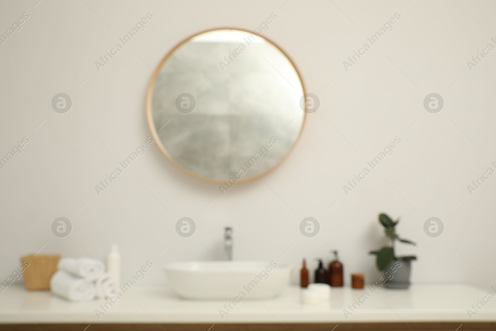 Photo of Blurred view of countertop with sink, towels, houseplant and mirror in bathroom