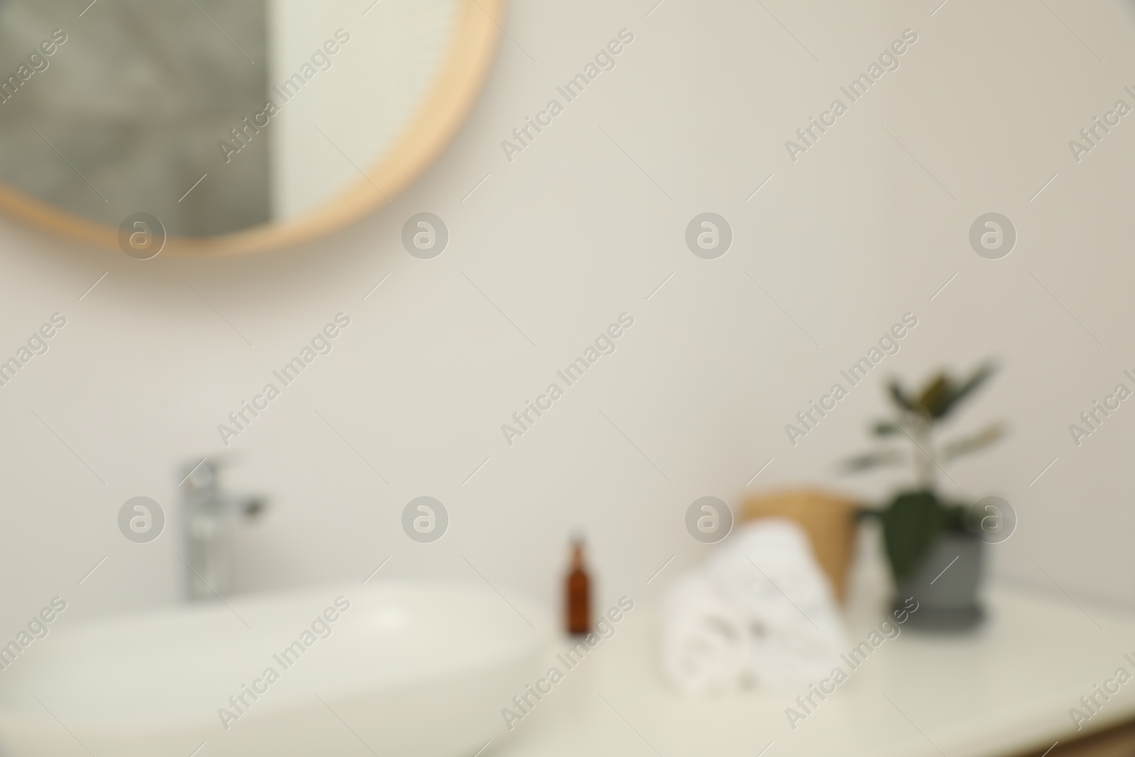 Photo of Blurred view of countertop with sink, towels, houseplant and mirror in bathroom