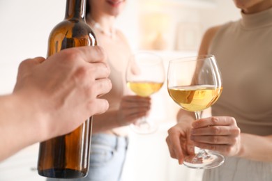 Photo of Friends with glasses of wine indoors, selective focus