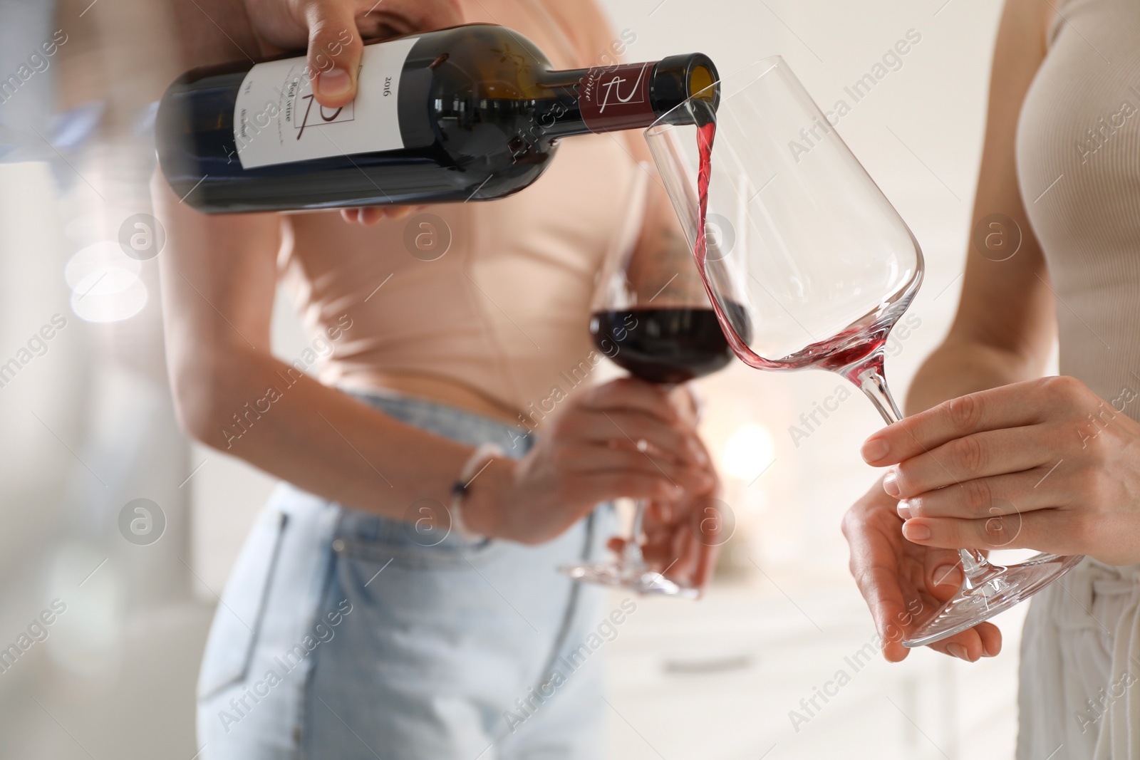 Photo of Man pouring red wine into woman`s glass indoors, selective focus