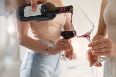 Man pouring red wine into woman`s glass indoors, selective focus