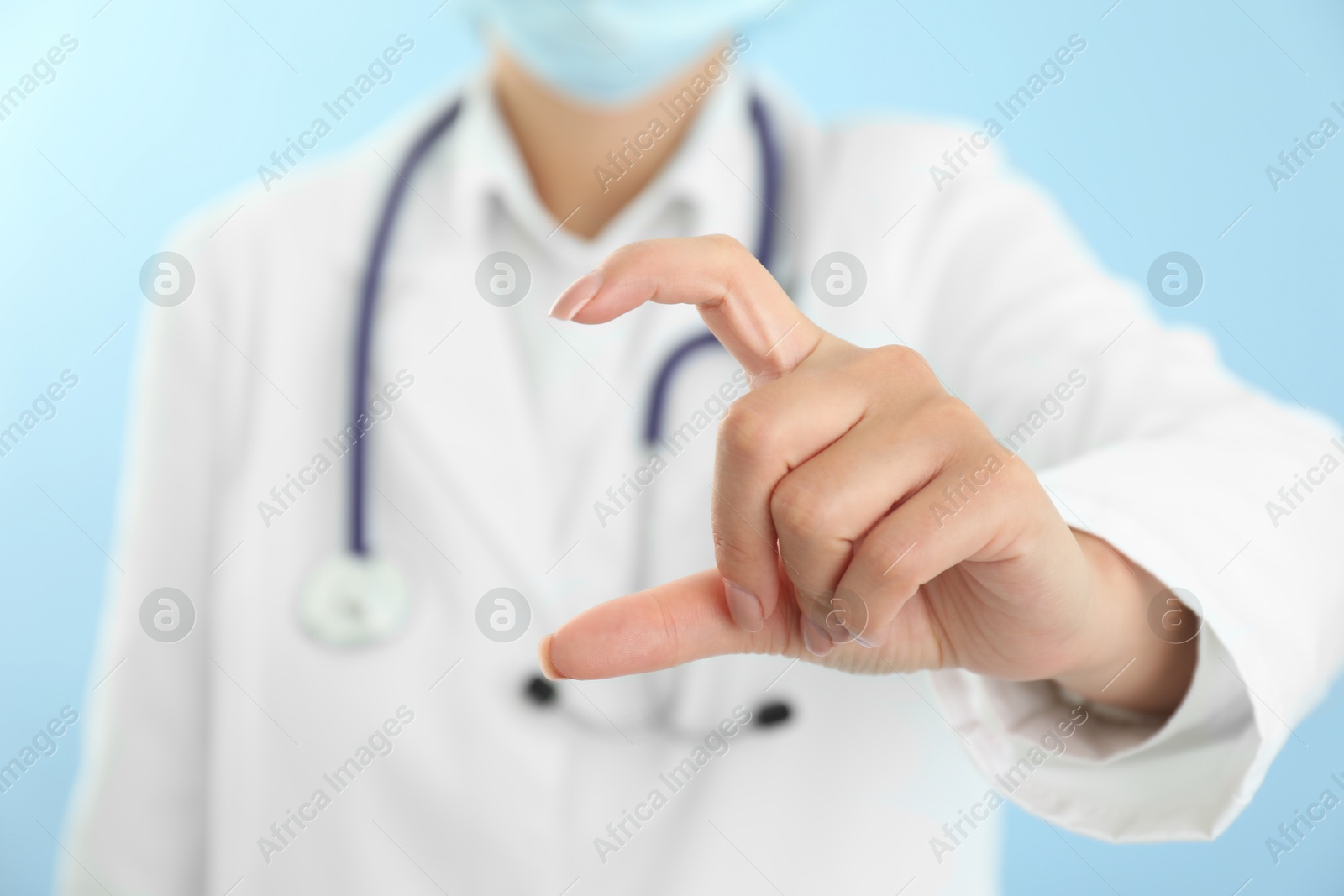 Photo of Doctor holding something on light blue background, closeup