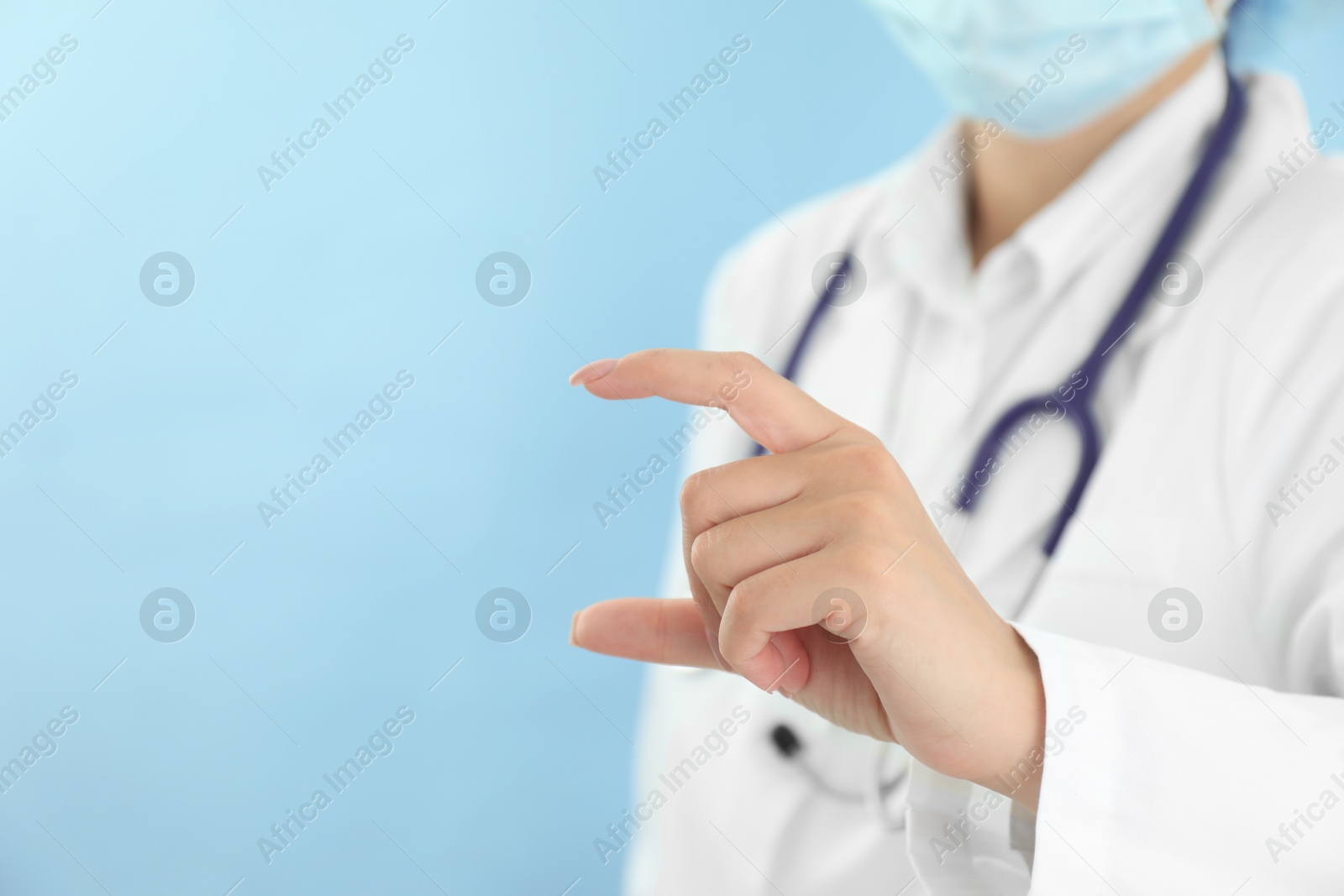 Photo of Doctor holding something on light blue background, closeup. Space for text