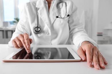 Photo of Doctor with tablet at table in clinic, closeup view