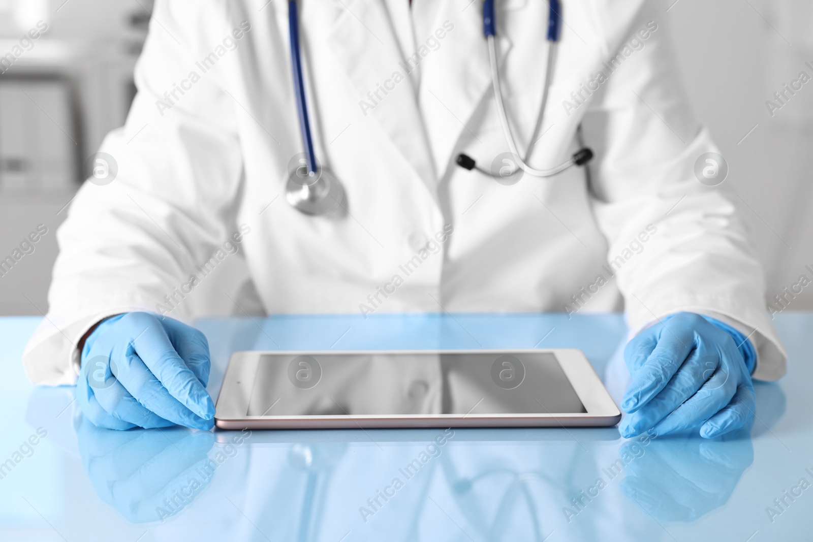 Photo of Doctor with tablet at table in clinic, closeup view