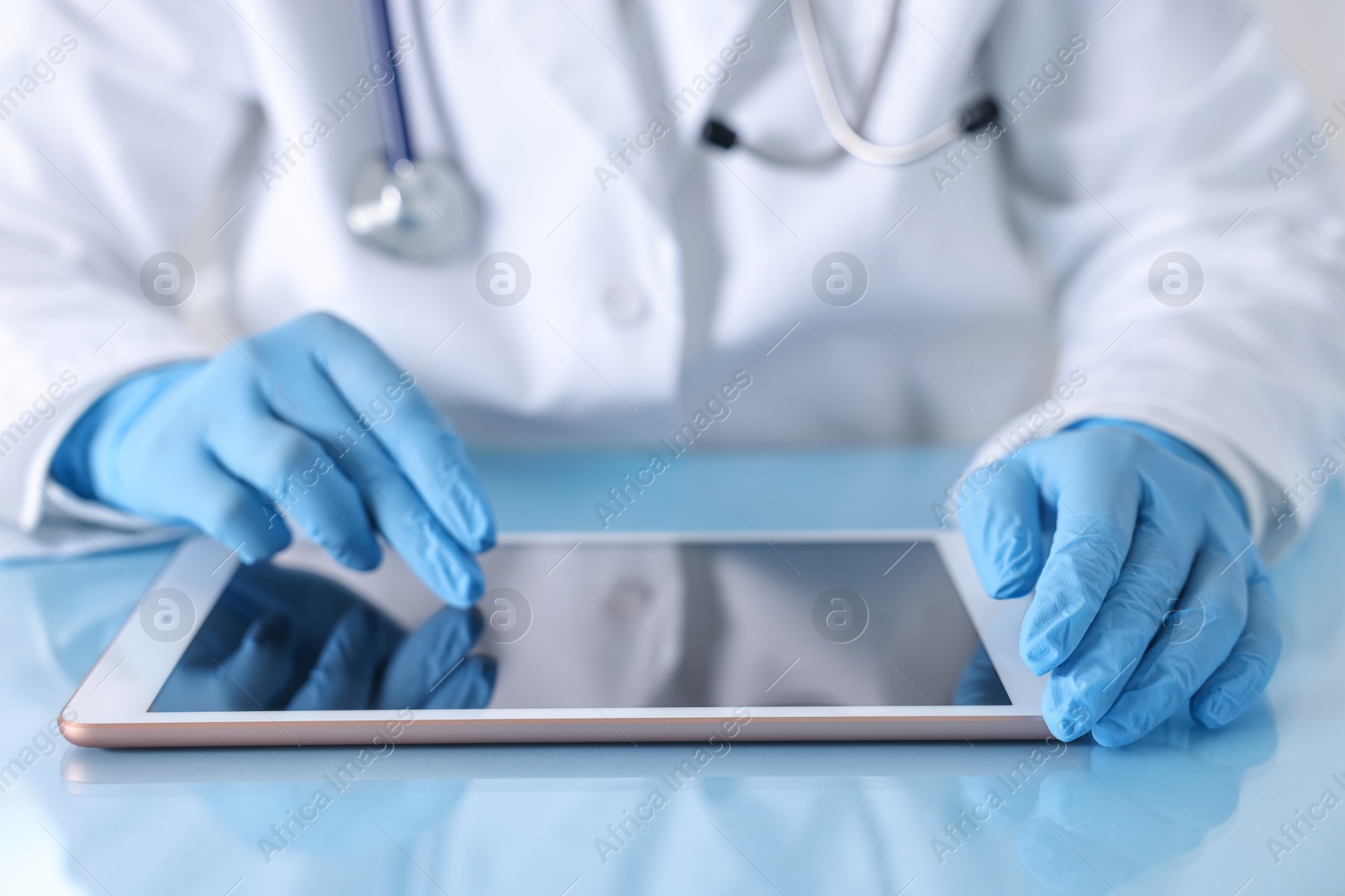 Photo of Doctor with tablet at table in clinic, closeup view