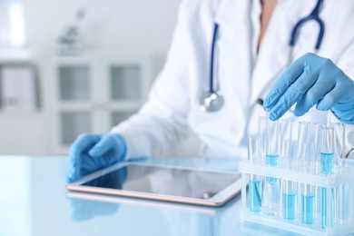 Doctor with tablet at table in clinic, closeup view