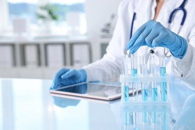 Photo of Doctor with tablet at table in clinic, closeup view