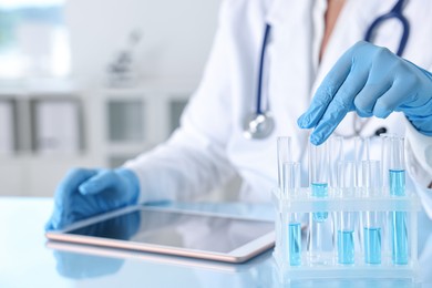 Photo of Doctor with tablet at table in clinic, closeup view