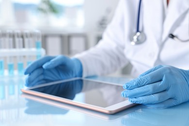 Photo of Doctor with tablet at table in clinic, closeup view