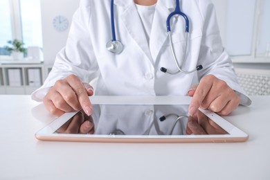 Photo of Doctor with tablet at table in clinic, closeup view